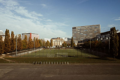 Empty road by buildings in city against sky