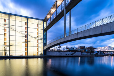 Bridge over river against sky in city at dusk