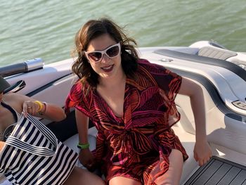 Young woman wearing sunglasses sitting on boat in water