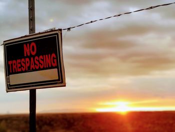 Information sign on road against sky during sunset