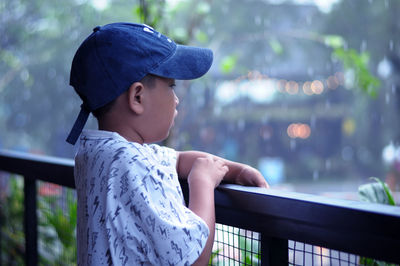 Boy looking away while standing by railing