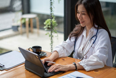 Businesswoman using laptop while sitting on table