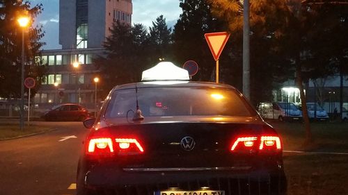 Cars on illuminated city street against sky at night