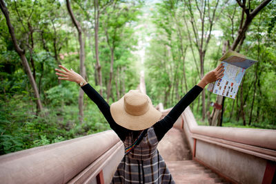 Rear view of person standing by plants in forest
