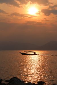 Silhouette boat in sea against sky during sunset
