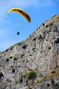 Low angle view of kite flying over mountain against sky