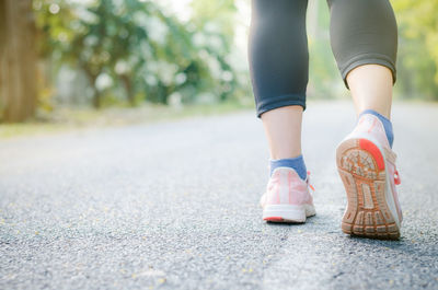 Low section of woman walking on road