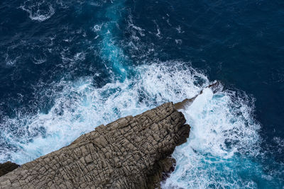 High angle view of waves splashing on rocks