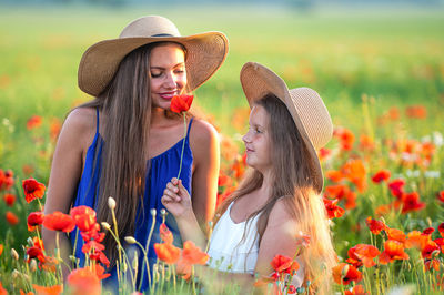 Side view of young woman looking away while standing by flowering plants