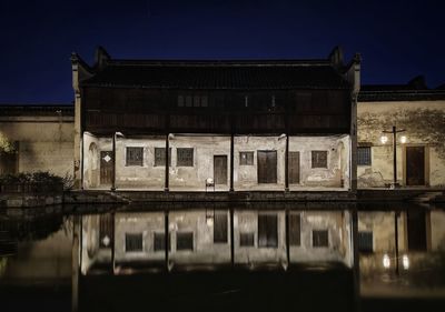 Building by lake against sky at night