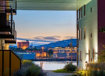 Illuminated buildings by city against sky at dusk