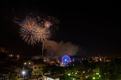 Firework display in city against sky at night