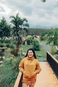 Portrait of young woman standing against sky