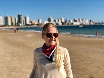 Smiling young woman standing at beach in city