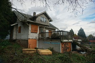 Exterior of abandoned house on field against sky