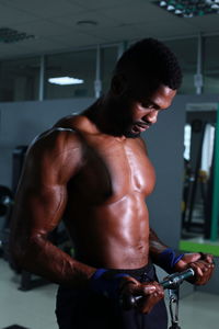 Shirtless confident athlete exercising in gym