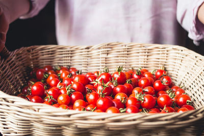 Close-up of hands holding cherry tomatoes in basket