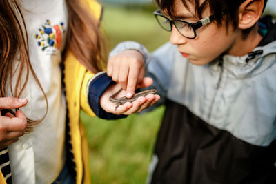 Midsection of woman holding lizard while boy touching it