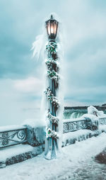 Frozen illuminated street light against cloudy sky