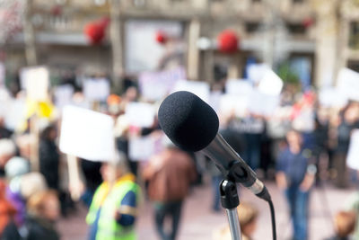 Close-up of microphone against people standing outdoors
