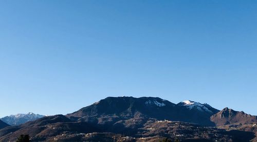 Scenic view of snowcapped mountains against clear blue sky