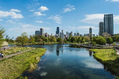 Scenic view of river by city against sky