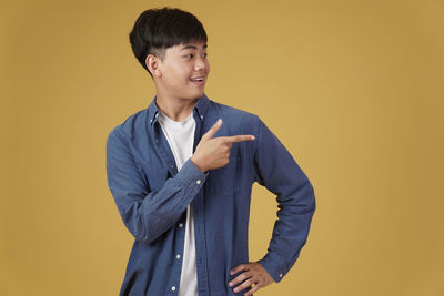 Side view of a smiling young man against yellow background