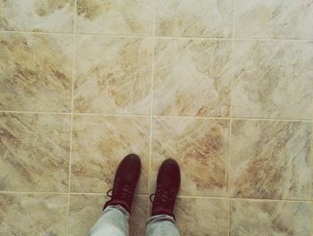 Low section of man standing on tiled floor