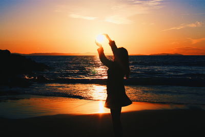 Silhouette of people on beach at sunset