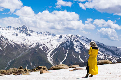 Rear view of man standing on snowcapped mountain