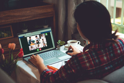 Rear view of man using laptop on table