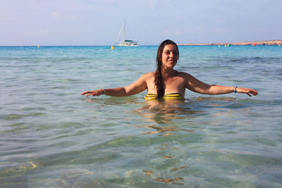 Young woman in sea against sky