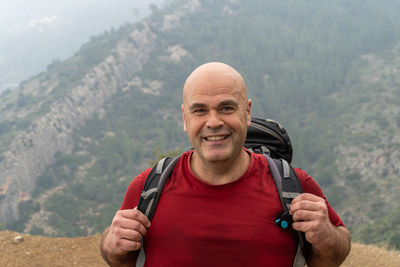 Portrait of caucasian man with shaved head, with a backpack practicing and enjoying the mountain.