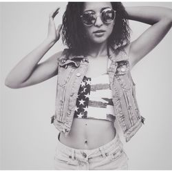 Portrait of young woman wearing sunglasses while standing against white background