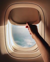 Cropped hand of person opening airplane window