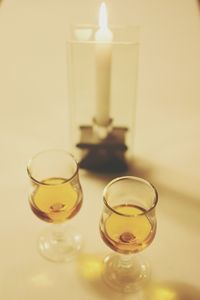 High angle view of wineglasses by burning candle on table