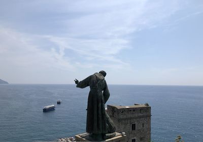 View of seagull on statue by sea against sky