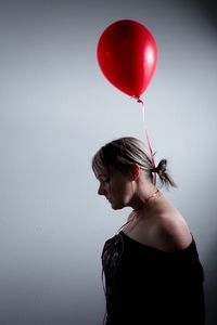 Close-up of woman with red balloons against wall