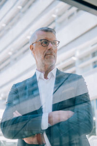 Low angle view of thoughtful senior businessman seen through window