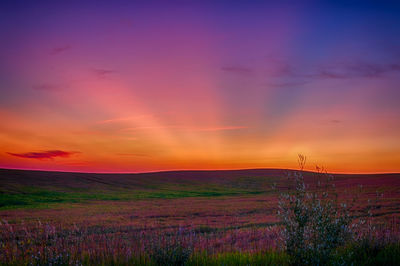 Scenic view of dramatic sky over land during sunset