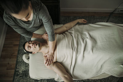 Female massage therapist applies pressure to male's shoulders