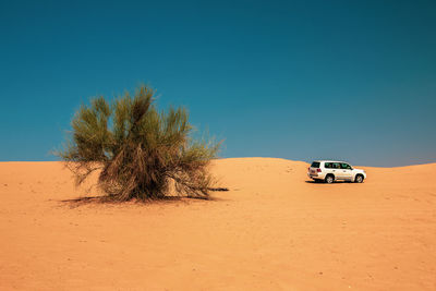 View of car on desert against clear sky