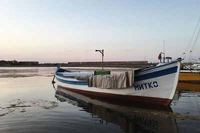 Boats moored in sea against clear sky during sunset