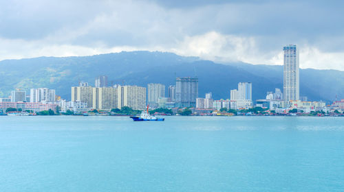 Sea by buildings against sky in city