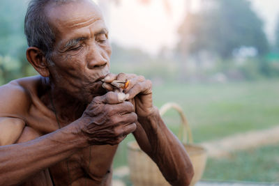 Close-up portrait of shirtless man holding outdoors