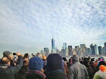 People photographing cityscape against cloudy sky