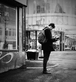 Full length side view of man walking on sidewalk against building in city