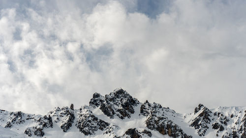 Scenic view of snow covered mountains against cloudy sky