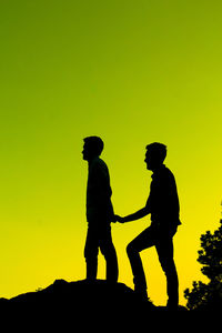 Silhouette men standing against clear sky during sunset