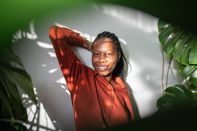 Portrait of young woman standing against plants